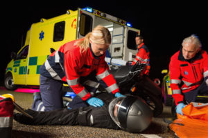 Paramedical team assisting injured man motorbike driver at night