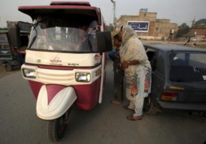 Pink Rickshaw driver Parveen Bibi speaks with prospective passengers in Lahore, Pakistan November 11, 2015. REUTERS/Mohsin Raza